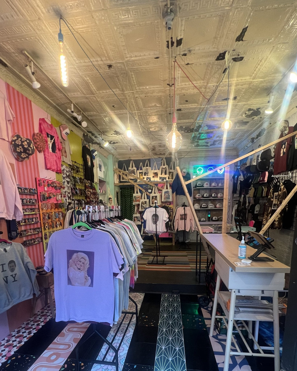 Inside Aliens of Brooklyn at 304 E 5th St: tee racks, cap wall, tote wall and the counter